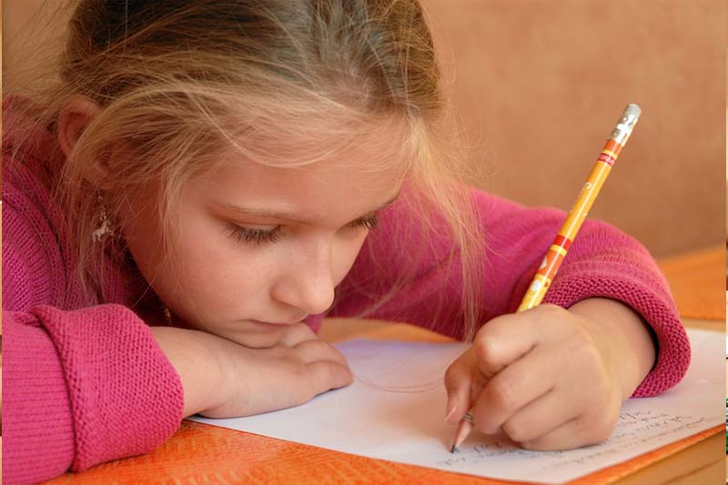 Schülerin denkt nach und schreibt mit Bleistift auf Papier - Integrative Lerntherapie in Darmstadt